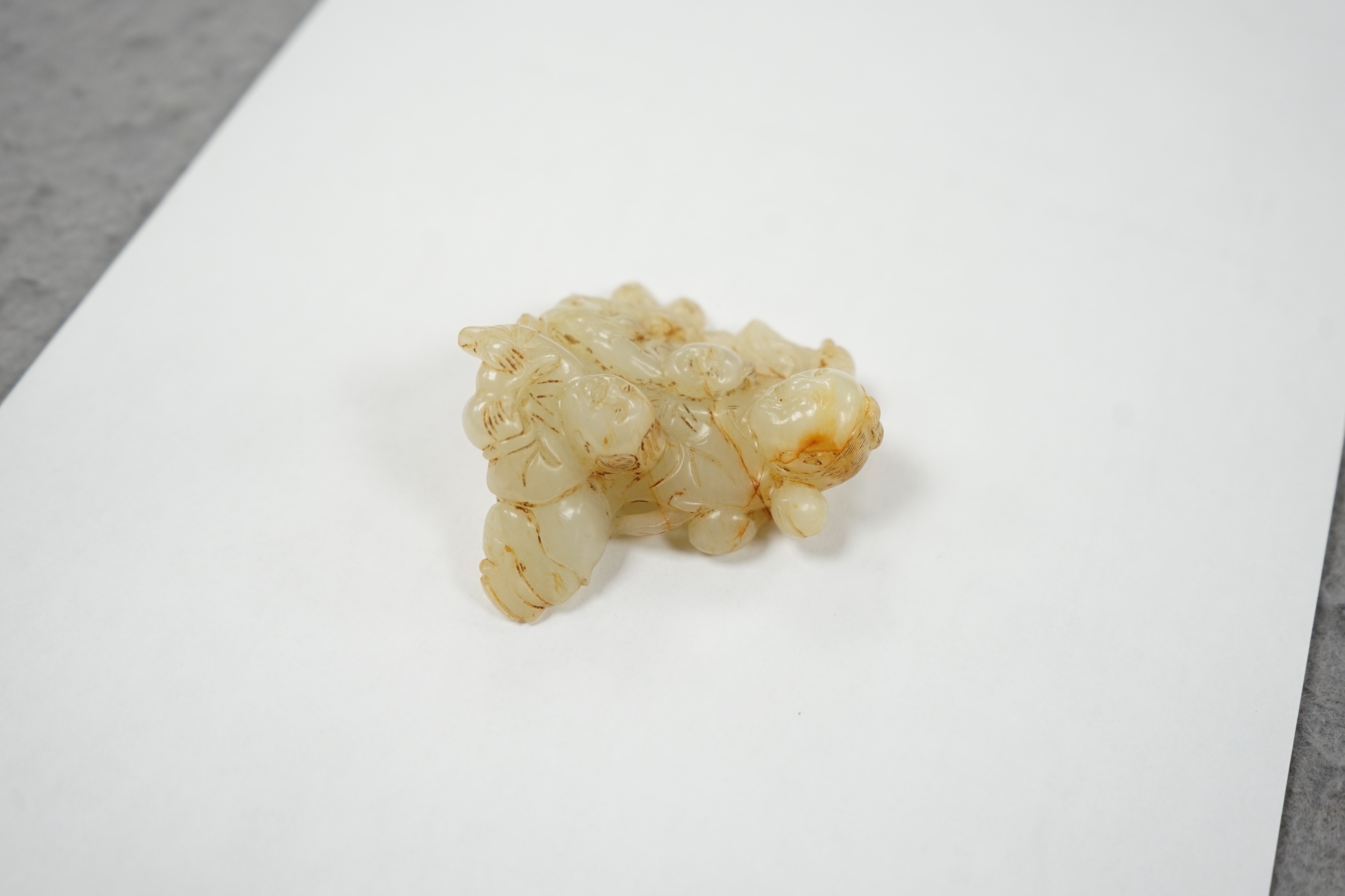 A Chinese white and russet jade group of three boys, 18th/19th century, 7.2 cm, wood stand